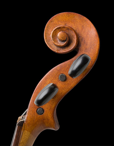 Antique violin scroll isolated on black background.