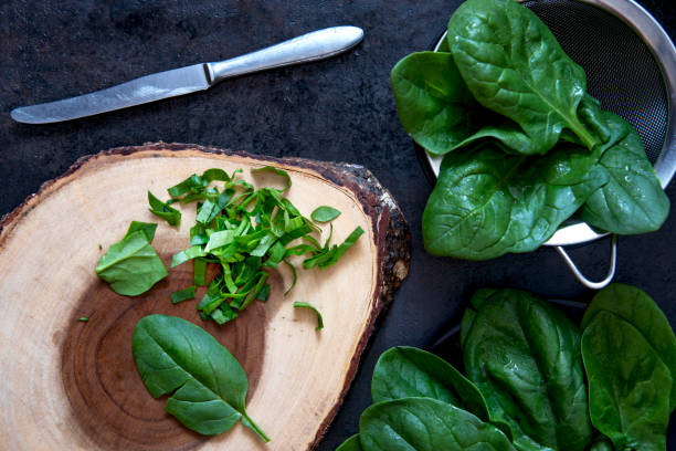 istock Fresh spinach on wooden cutting board with knife on dark background. Top view 1234427358