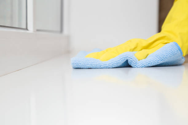 istock Cleaner hand in yellow rubber protective glove wiping white plastic window sill from dust with blue dry rag. General or regular cleanup. Cleaning service. Closeup. Low angle view. 1234486719