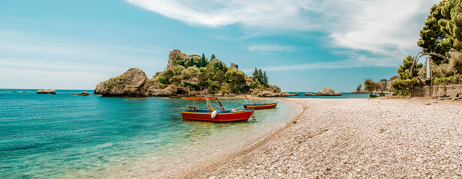 Wide angle panorama of the La Isola Bella beach in Taormina, Sicily, Italy, seen a hot summer day.