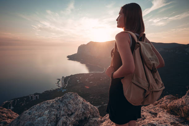 istock Young woman with backpack enjoys the view at sunset. 1234511178