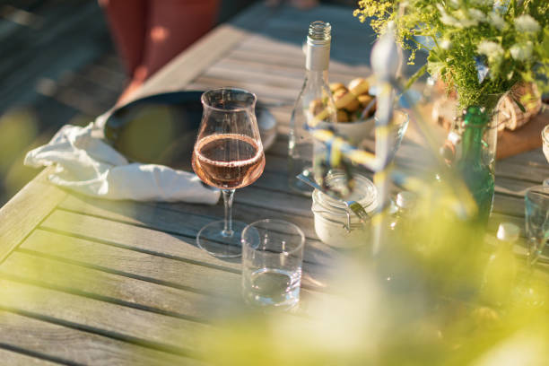 A glass of rosé wine Firar midsommar med traditionellt smörgåsbord, med sill, nubbe (snaps) och rosévin. outdoor dining photos stock pictures, royalty-free photos & images