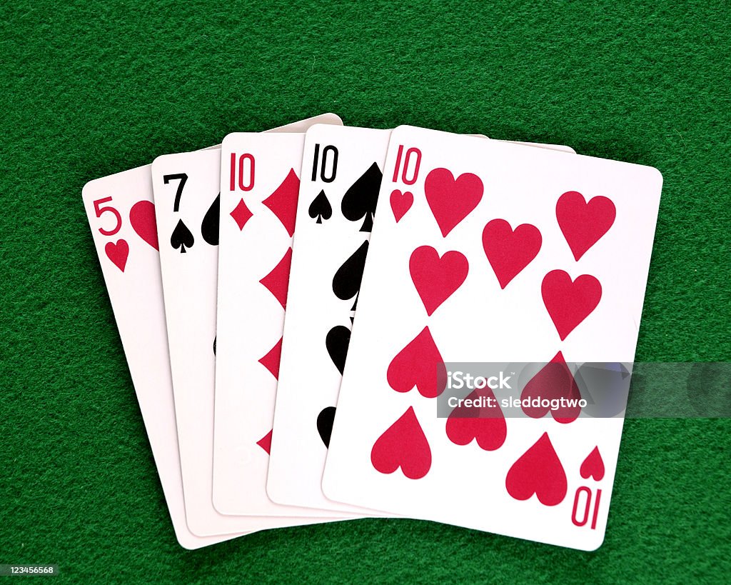 Poker Hand, Three of a Kind A poker hand "three of a kind" or a "set", this one is 3 tens, with a 5 and a seven on a green felt background. Black Color Stock Photo