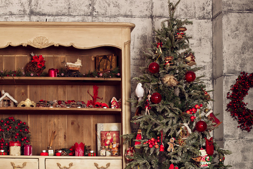 Christmas card and background. Christmas tree and old wardrobe decorated with red balls, toys and decor.