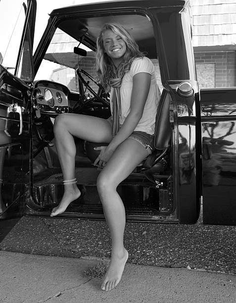 An attractive young woman with beautiful legs and barefoot,getting out of a vintage pickup truck.