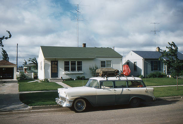 1956 Chevrolet parked in front of 50's home 1956 Chevrolet station wagon packed for vacation in front of new tract house with TV antenna. Symbols of the affluent post WWII society in USA. Waterloo, Iowa, 1957. Kodachrome scanned film with grain. small town america photos stock pictures, royalty-free photos & images