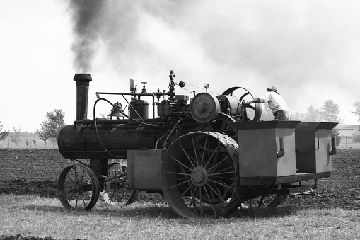 Steam tractor plowing a field. Plow is out of image but plowed furrows are in the background. Iowa, USA. Scanned film with grain.