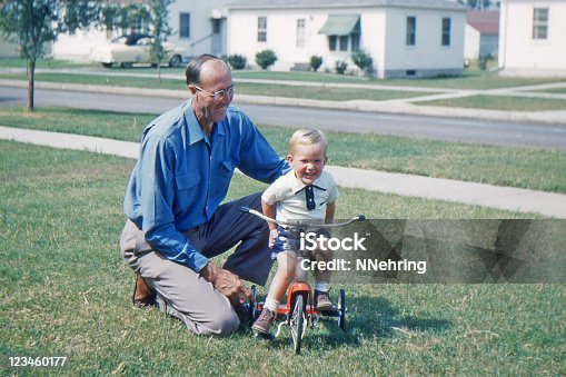 istock grandfather teaching grandson to ride tricycle 1953, retro 123460177