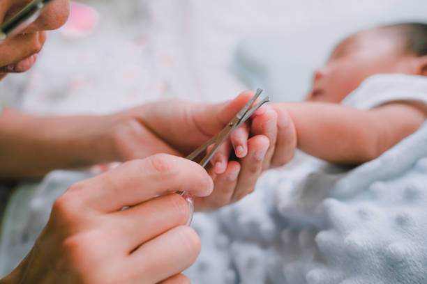 Close up photo for the mother cutting the finger nails of the baby. stock photo