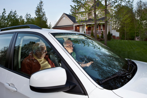 Two men parked in front of house waiting to pick someone up. Driver entering GPS coordinates.