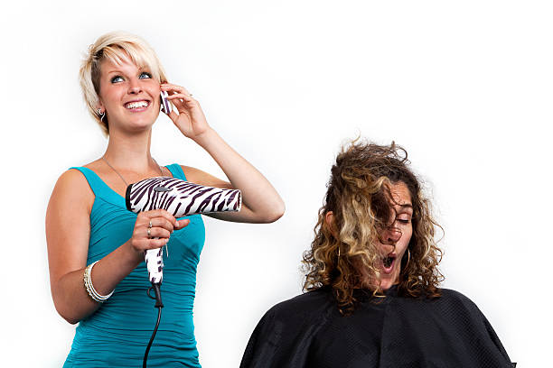 Distracted hairdresser on the phone Distracted hair stylist talking on the phone instead of paying attention to her work. angry hairstylist stock pictures, royalty-free photos & images