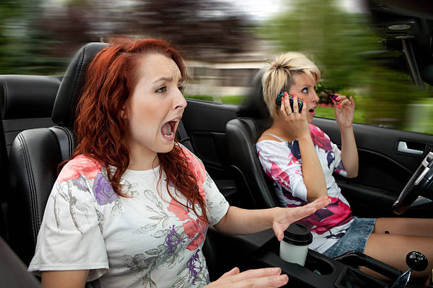 Dangerous Driving Passenger freaking out while driver applying makeup and talking on the phone. No one wearing seatbelts. maiden stock pictures, royalty-free photos & images