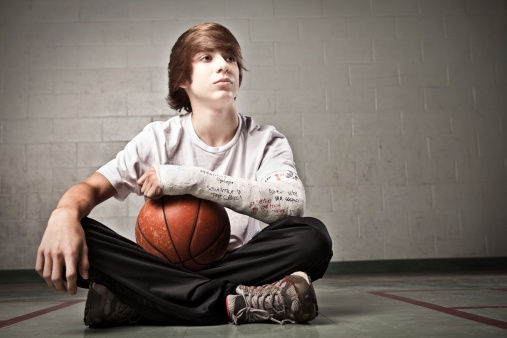 Teenager with broken arm wishing he could play basketball with his teammates.