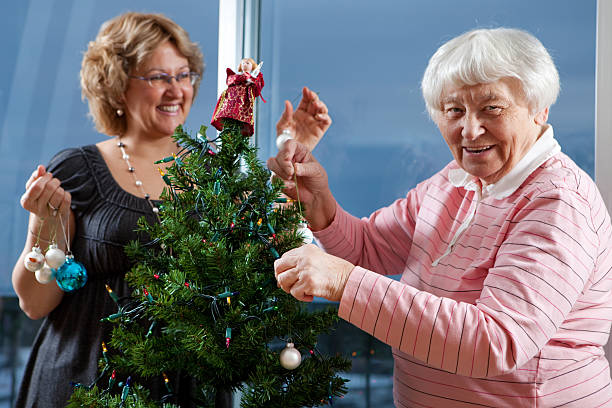bénévole aidant senior décorer l'arbre de noël - senior adult photograph photography family tree photos et images de collection