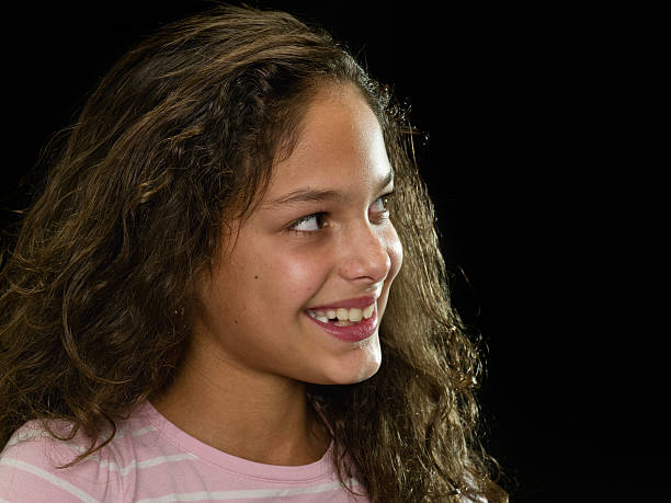 Ten years old hispanic little girl posing looking away smiling  on black background (this picture has been shot with a super high definition Hasselblad HD3 II 31 megapixels camera)