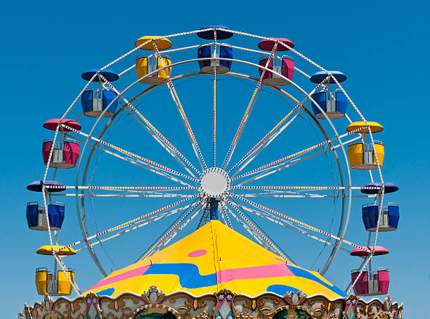 Ferris Wheel and Carousel Top Ferris Wheel and Carousel Top - colorful fair rides against blue sky midway fair stock pictures, royalty-free photos & images