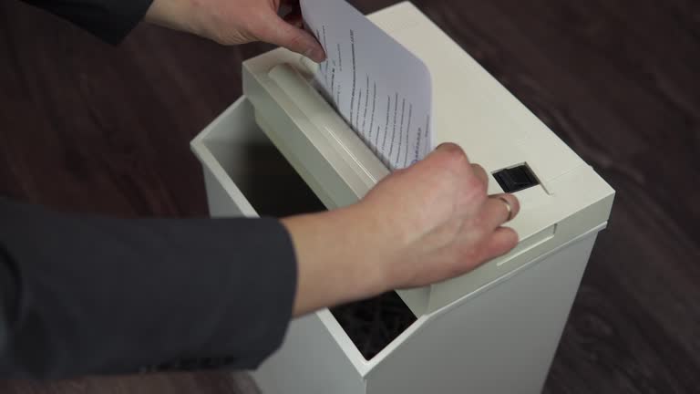 Shredder destroys documents. Businessman in a suit puts a sheet of paper into a paper shredder