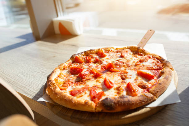 istock Big pizza stands on a table in a cafe. Italian pizza cut on pieces. 1234707202