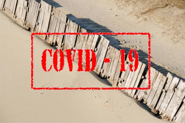 Photo of Empty sandy beach closed due to coronavirus or covid 19 virus pandemic safety social distancing lock down