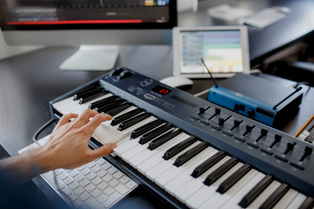 istock composer hands on piano keys in recording studio. music production technology, man is working on pianino and computer keyboard on desk. close up concept. 1234729574