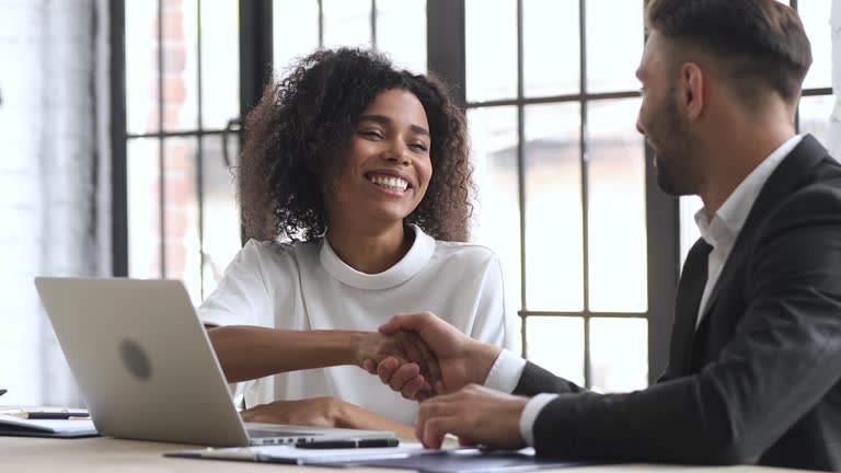 Smiling young african ethnicity businesswoman making agreement with male partner.