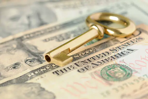 Photo of Gold Key to Success over United States Dollars in Cash