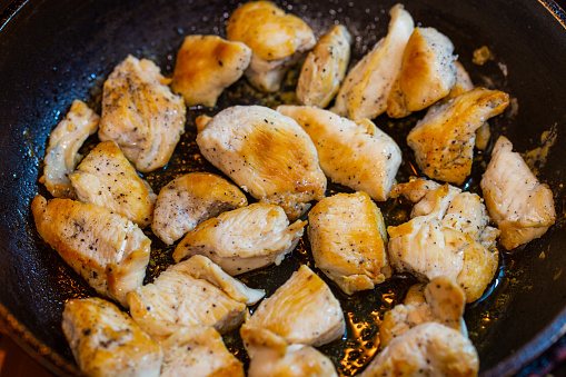 fried chicken in a pan with ground black pepper.
