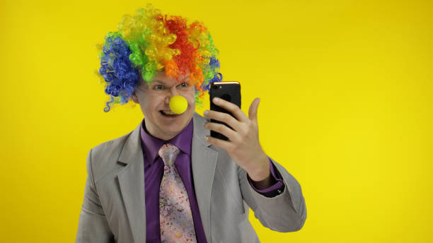 clown businessman entrepreneur in wig using app on smartphone for online work - clown circus telephone humor imagens e fotografias de stock