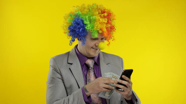 клоун бизнесмен предприниматель босс получает денежный доход при использовании смартфона - clown circus telephone humor стоковые фото и изображения