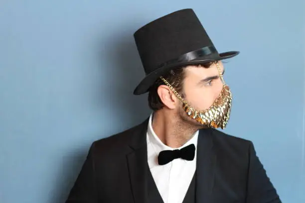 Gentleman in a tuxedo wearing golden face mask.