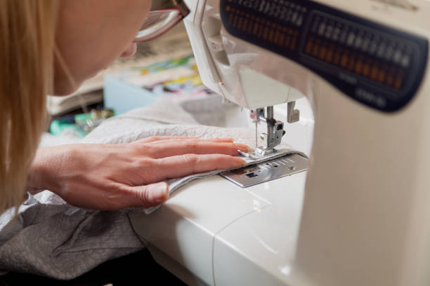 istock woman in glasses sews on modern sewing machine 1234896302