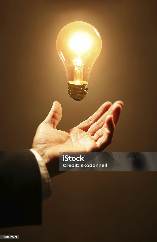 Glowing light bulb above a man's hand  Light Bulb Stock Photo