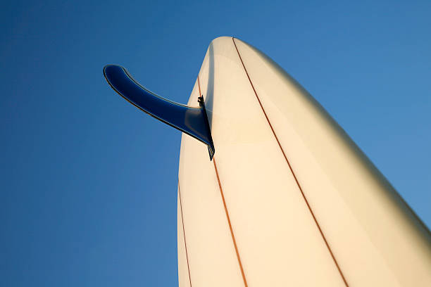 surfboard fin with blue sky background selective focus runs through the front edge of the fin and falls off quickly. surfboard fin stock pictures, royalty-free photos & images