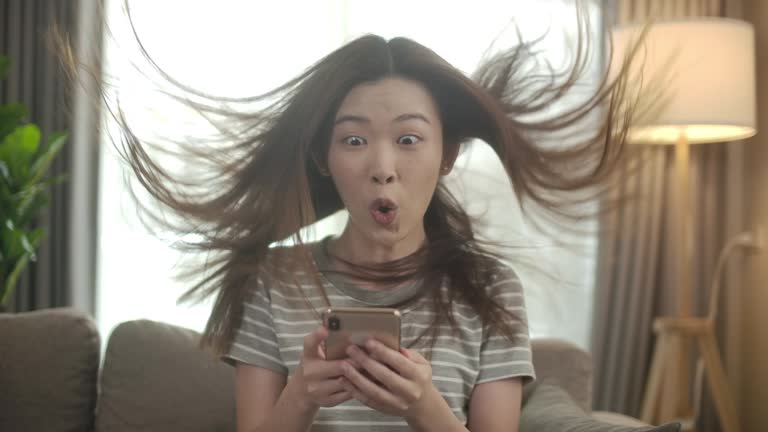 Slow motion Excited Asian woman using Smart phone, Phone prize winner. Good news girl punching the air