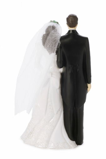 Subject: A humorous wedding cake figurines with the bride chasing and catching the terrified groom in the act of escape.