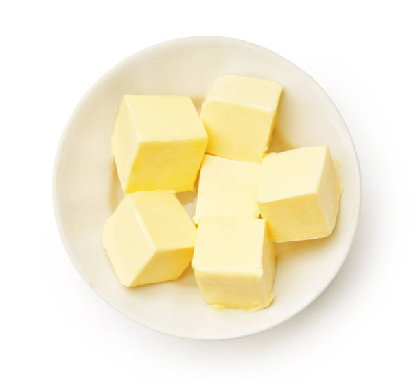 morceaux de beurre dans un bol blanc isolé. cubes de beurre. vue du haut. - butter fat dairy product isolated photos et images de collection