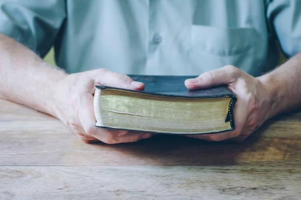 istock man hands holding holy bible on wooden table 1234980827