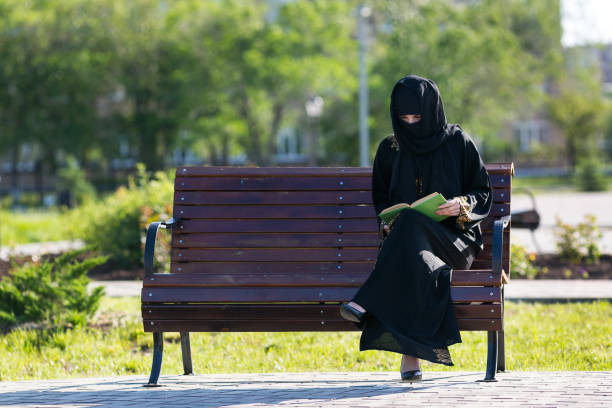 istock Muslim woman is reading a book on a bench. 1234985473