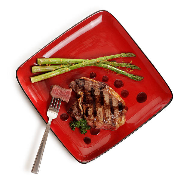 Main dish in restaurant. Grilled vegetables with duck steak and sauce served on plate.
