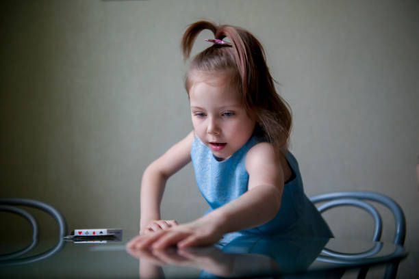fille de cinq ans avec des cartes de jeu dans ses mains - board game piece leisure games blue isolated photos et images de collection