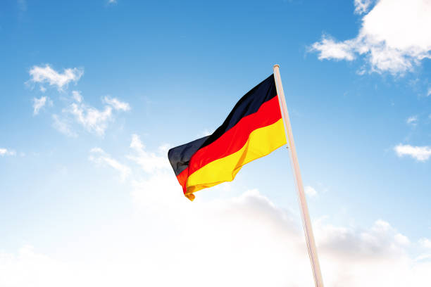istock A German flag in front of clouds in blue sky 1235023553
