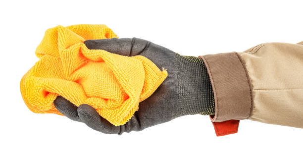 istock Crumpled orange microfiber cloth in worker hand in black protective glove and brown uniform isolated on white background 1235051234