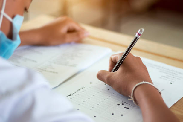 students in uniform are doing the test in the classroom - junior high fotos imagens e fotografias de stock