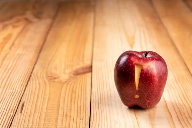 Close-up image of a vibrant red coloured juicy apple precisely carved with exclamation mark sigh placed on white polished red pine floor boards in studio. Ideal for many concept with plenty of copy space for your message, concepts and ideas: Ripe Fruit, Healthy Lifestyle, Warning sigh, Healthcare And Medicine, Carving - Craft Product. Shot on Canon EOS R with premium lens for highest quality.