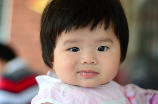 An Asian baby making face at the camera.