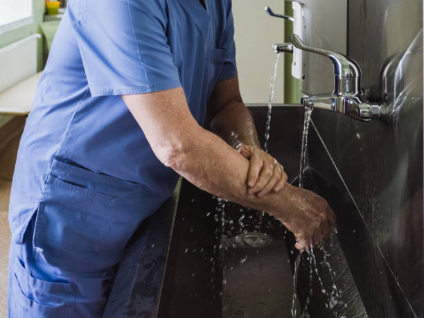 의사는 스테인레스 스틸 싱크대에서 수돗물 아래에서 손을 세탁합니다. - hospital acquired infection 뉴스 사진 이미지