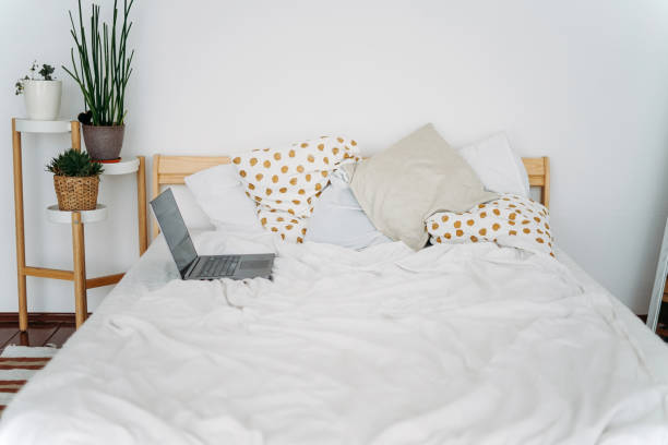 istock Opened laptop notebook on bed at bright scandinavian interior work from home freelance concept 1235138540