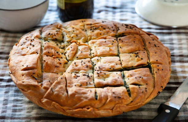 шпинат пирог греческий spanakopita круглую форму на фоне кухонного стола - pie spinach spanakopita filo pastry стоковые фото и изображения