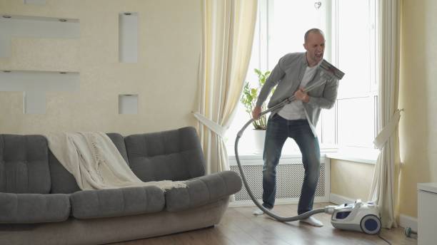 istock Man playing on vacuum cleaner like on guitar, having fun during house cleaning 1235154083