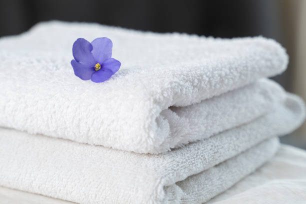 istock Spa composition on the table. A stack of two white fluffy bath towels with a flower 1235157687